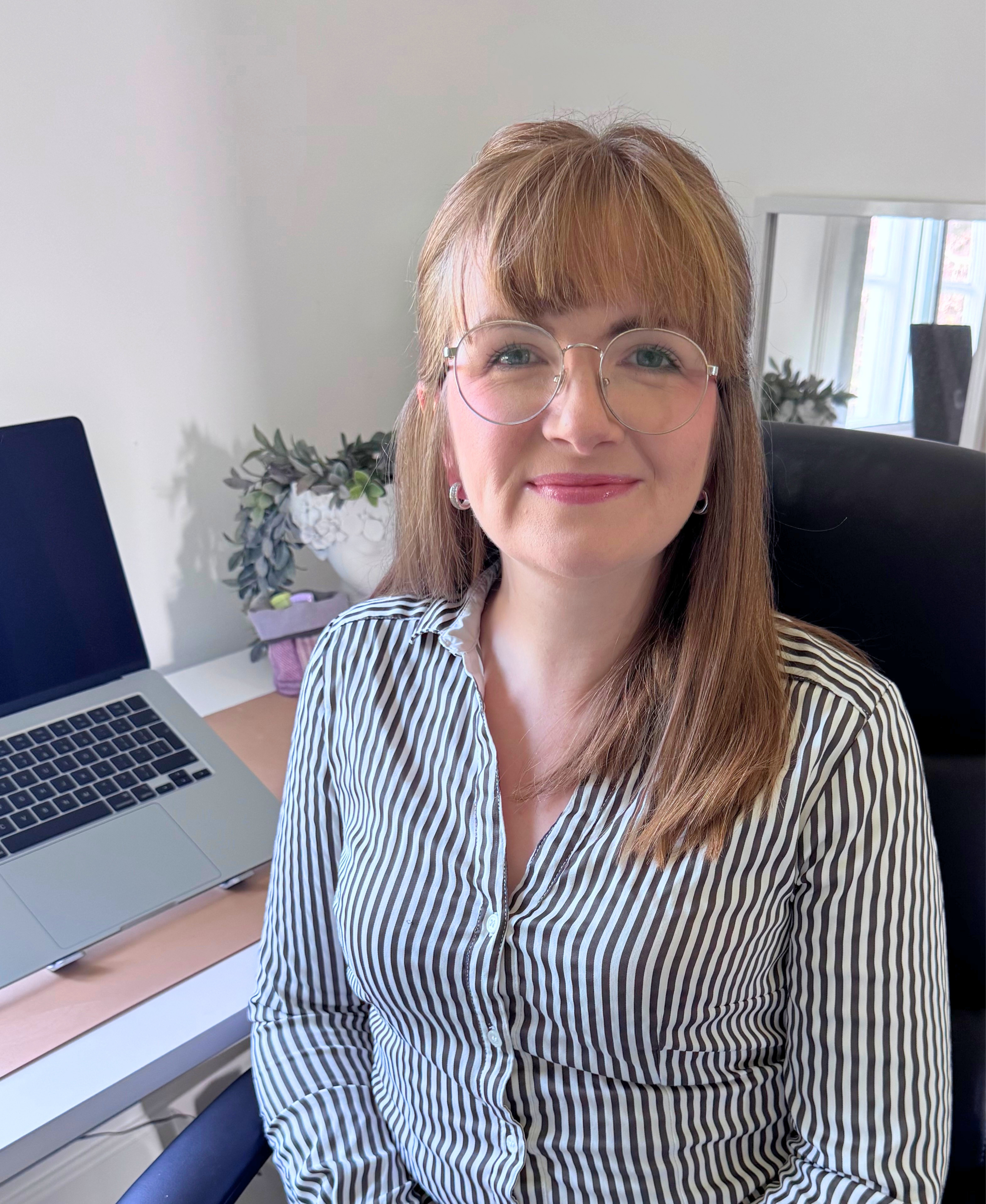 Deborah Orr smiling at her desk beside her laptop