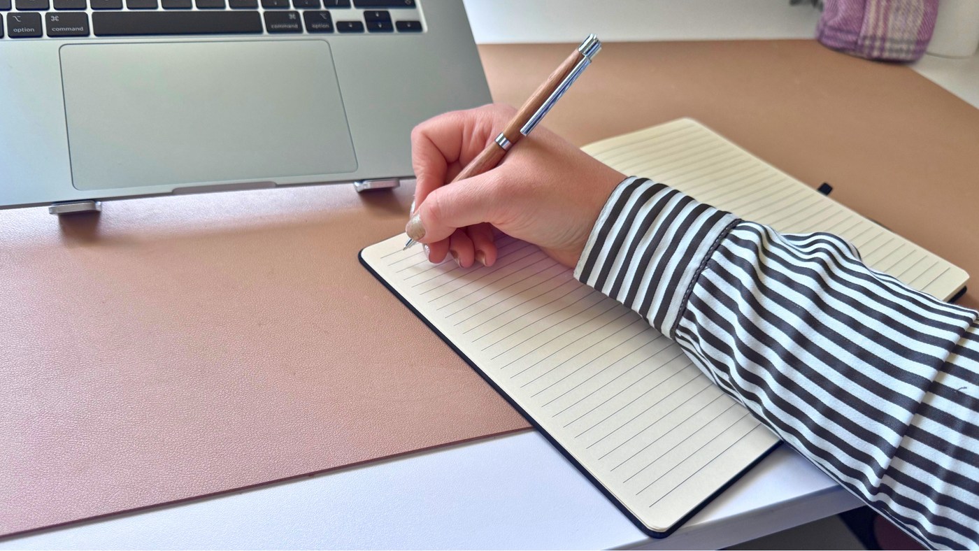 Writing notes beside a laptop